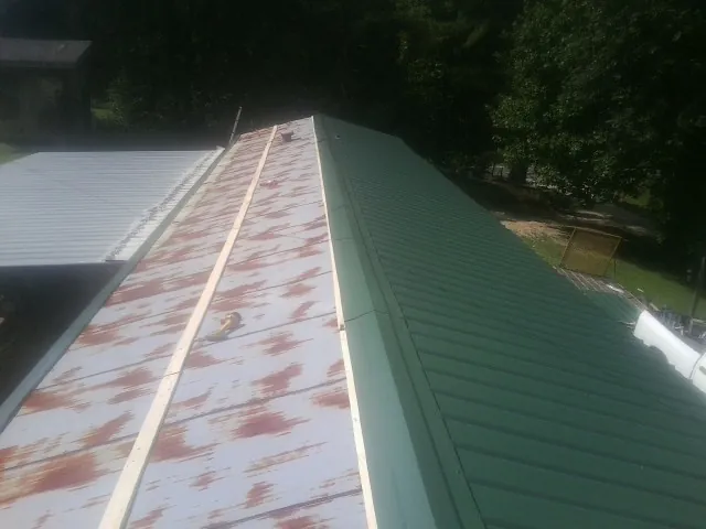 Old rusted panels beside newly installed green metal roofing — Wind Damage Roof Repair by Roofing Brothers in Little Rock