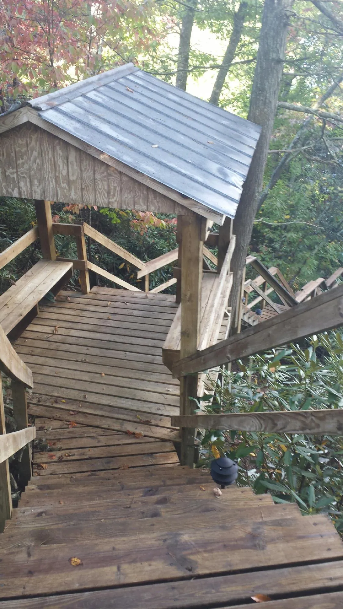 Metal roofed shelter over wooden steps on a wooded walkway — Skylight Repair & Installation work by our crew in Little Rock