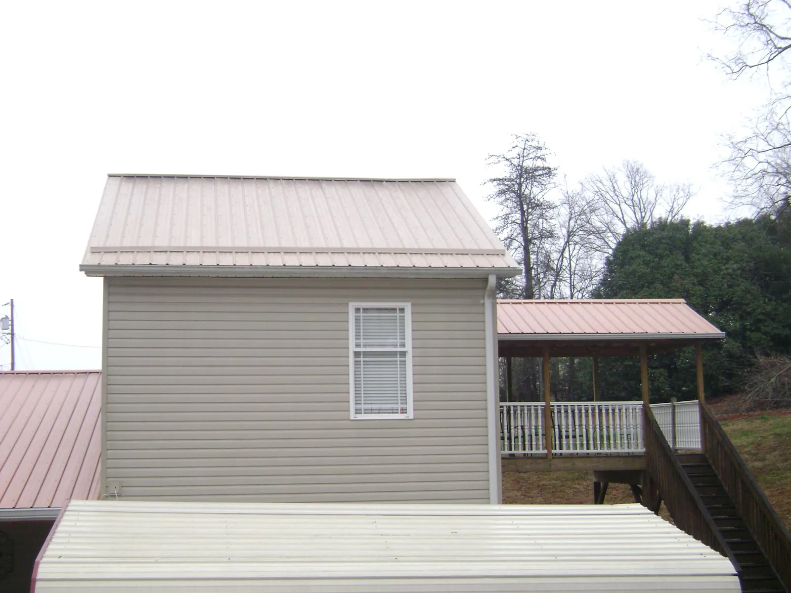 Tan metal roofs on a two story addition and attached porch, from a Roof Replacement job in Little Rock